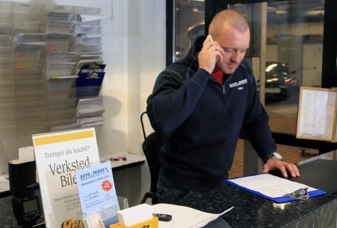 Ansatt på Auto Skade snakker i telefonen